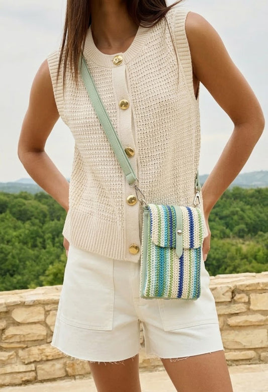 Person wearing a colorful striped handbag with a blurred floral background