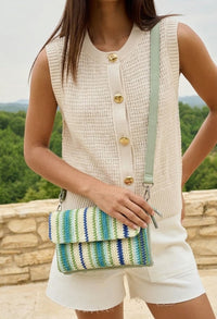 Person holding a striped handbag with a scenic background