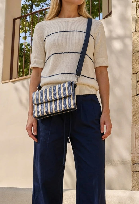 Person holding a colorful striped handbag with a scenic background