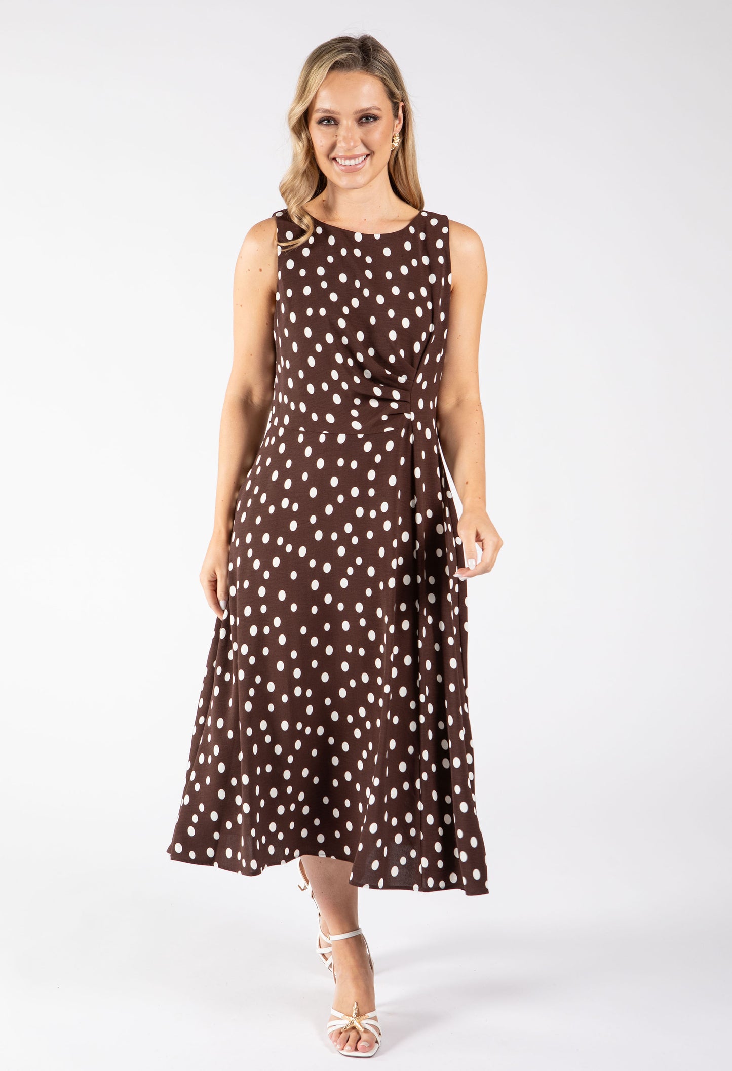 Woman wearing a brown dress with white polka dots on a white background