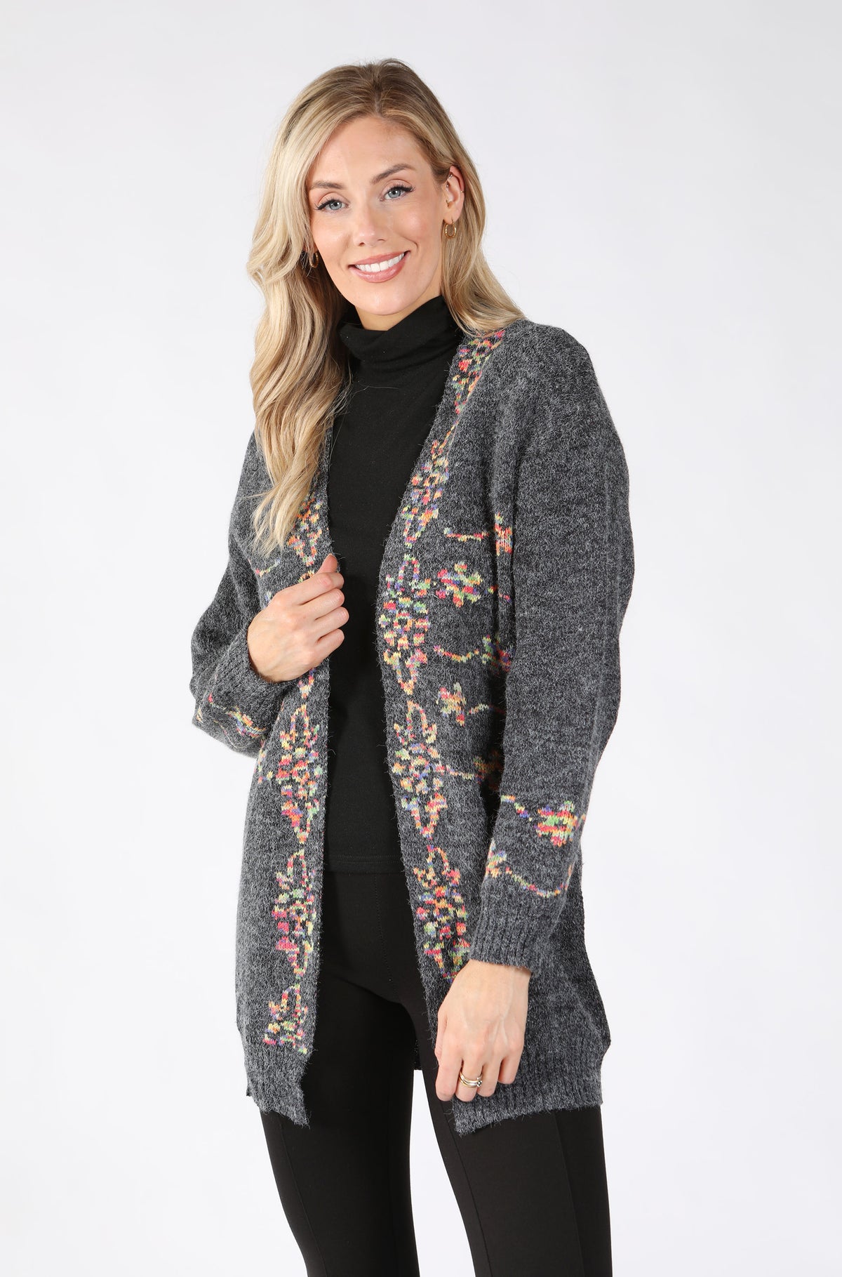 A woman modeling a dark gray open-front cardigan with colorful floral patterns along the front and long sleeves.