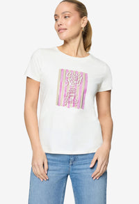 Woman wearing a white t-shirt with a colorful graphic design on a plain background