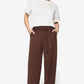 Woman wearing a white top and brown wide-leg pants on a white background