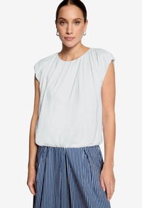Woman wearing a white sleeveless top and blue striped pants on a white background