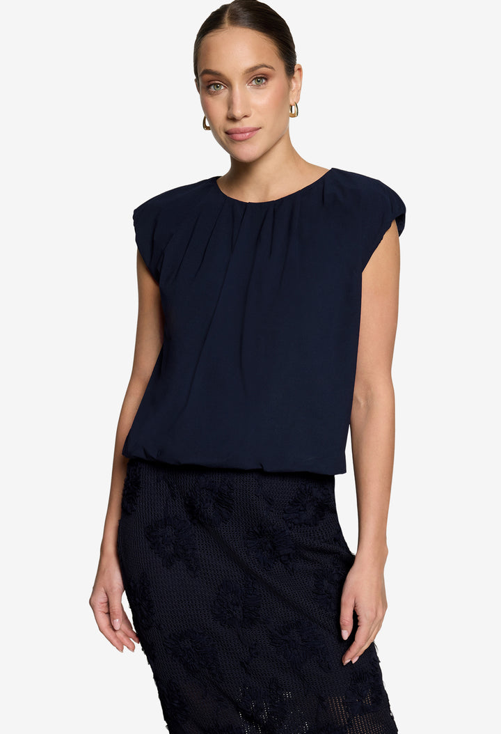 Woman wearing a black sleeveless navy with a plain background