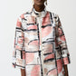 Woman wearing a colorful abstract patterned jacket on a white background