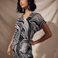 Woman wearing a black and white patterned dress against a beige background