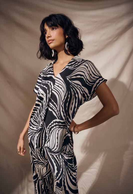 Woman wearing a black and white patterned dress against a beige background
