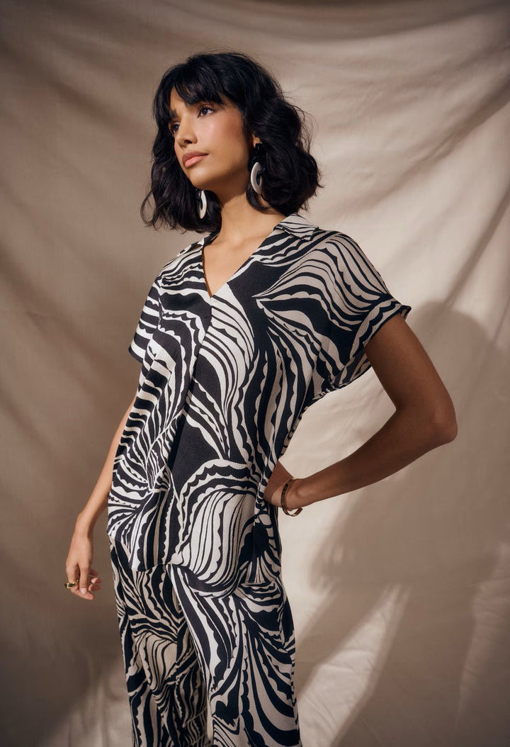 Woman wearing a black and white patterned dress against a beige background
