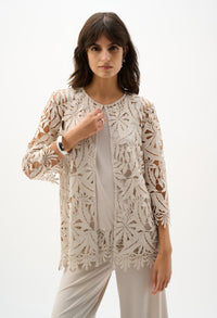 Woman wearing a beige lace jacket over a white top and pants on a white background