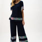 Woman wearing a navy outfit with colorful patterns on a white background