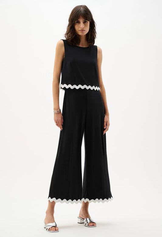 Woman wearing a navy jumpsuit with white trim on a white background
