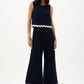 Woman wearing a navy jumpsuit with white trim on a white background