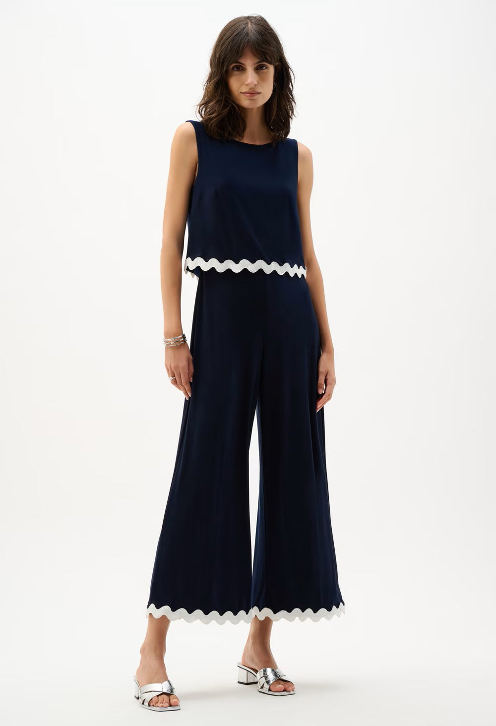 Woman wearing a navy jumpsuit with white trim on a white background