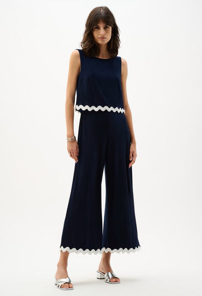 Woman wearing a navy jumpsuit with white trim on a white background