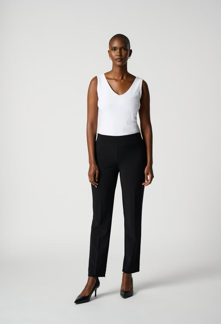 Woman wearing a white sleeveless top and black pants on a white background