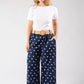 Woman wearing a white t-shirt and navy polka dot pants on a white background