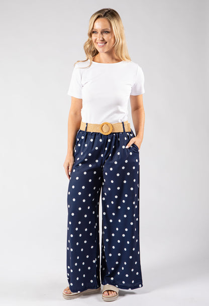 Woman wearing a white t-shirt and navy polka dot pants on a white background