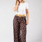 Woman wearing a white top and brown polka dot pants on a white background
