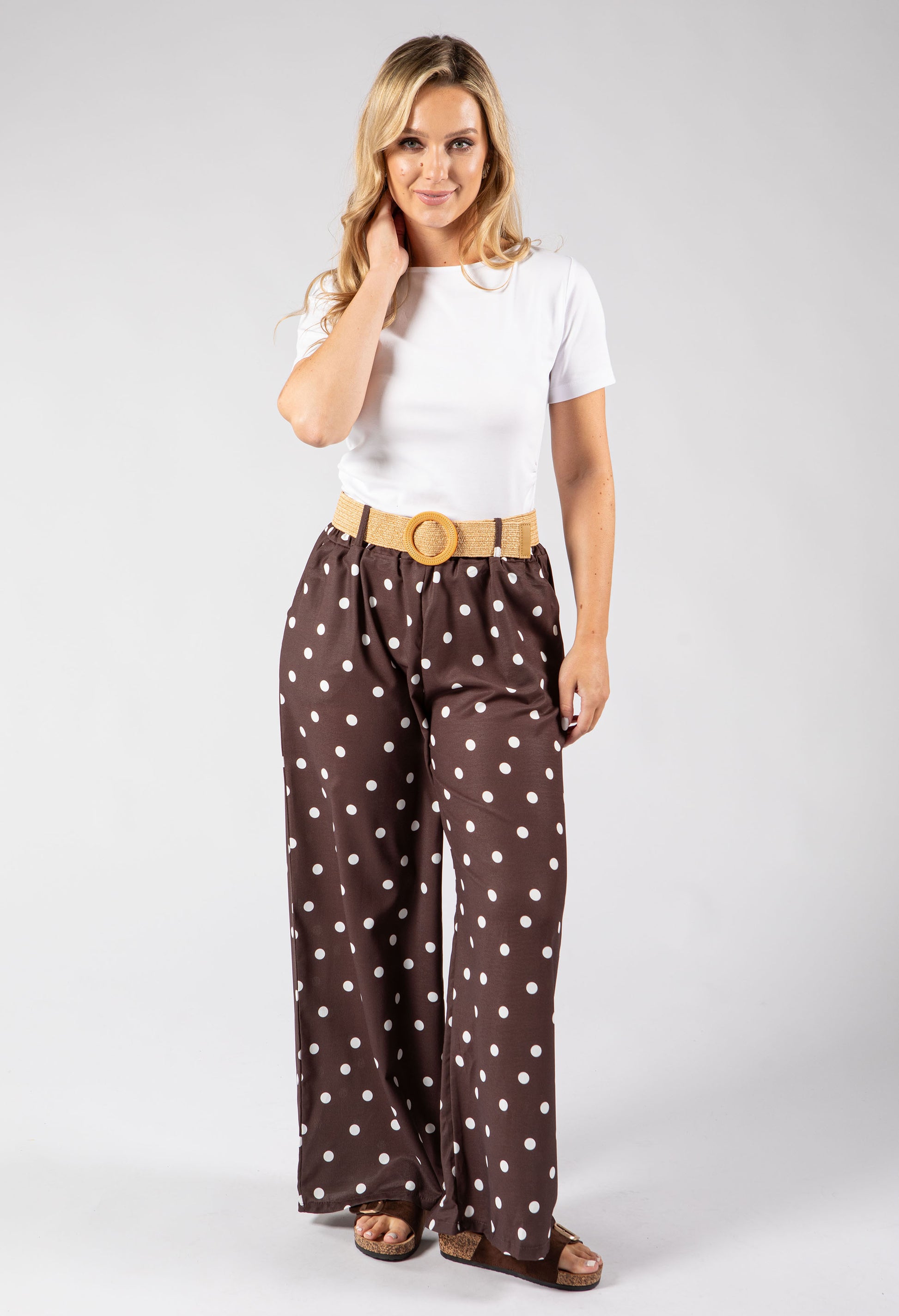 Woman wearing a white top and brown polka dot pants on a white background