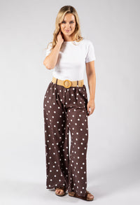 Woman wearing a white top and brown polka dot pants on a white background