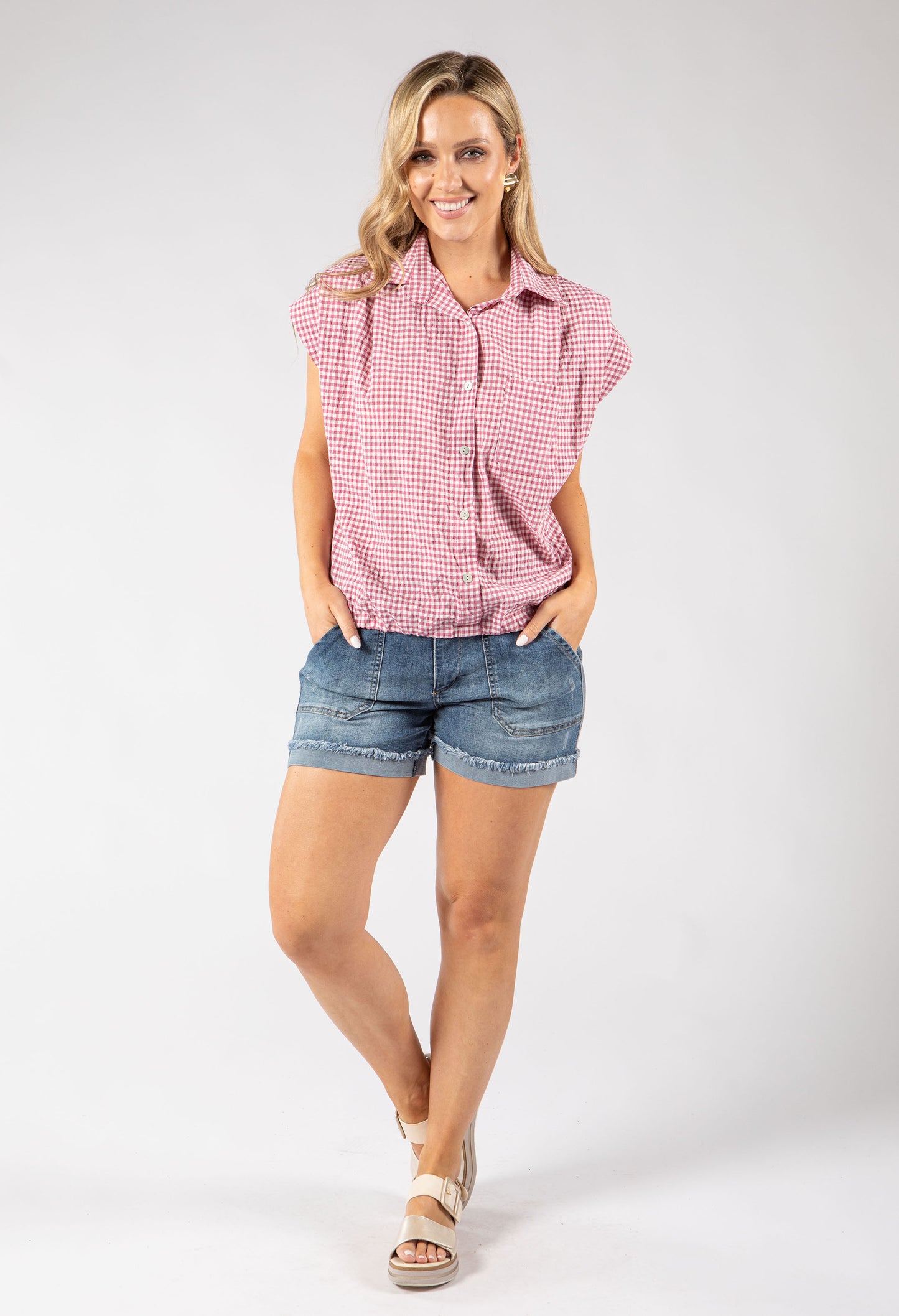 Woman wearing a red and white checkered shirt and denim shorts on a white background