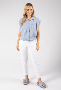 Woman wearing a blue checkered shirt and white pants on a gray background
