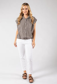 Woman wearing a checkered shirt and white pants on a plain background