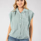 Woman wearing a green checkered shirt and denim shorts on a white background