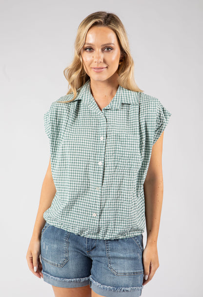 Woman wearing a green checkered shirt and denim shorts on a white background