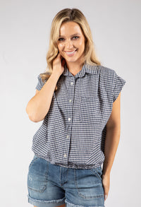 Woman wearing a checkered shirt and denim shorts on a plain background
