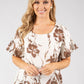 Woman wearing a floral blouse with brown leaf patterns on a white background