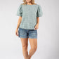 Woman wearing a green checkered top and denim shorts on a white background