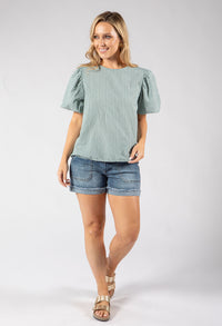 Woman wearing a green checkered top and denim shorts on a white background