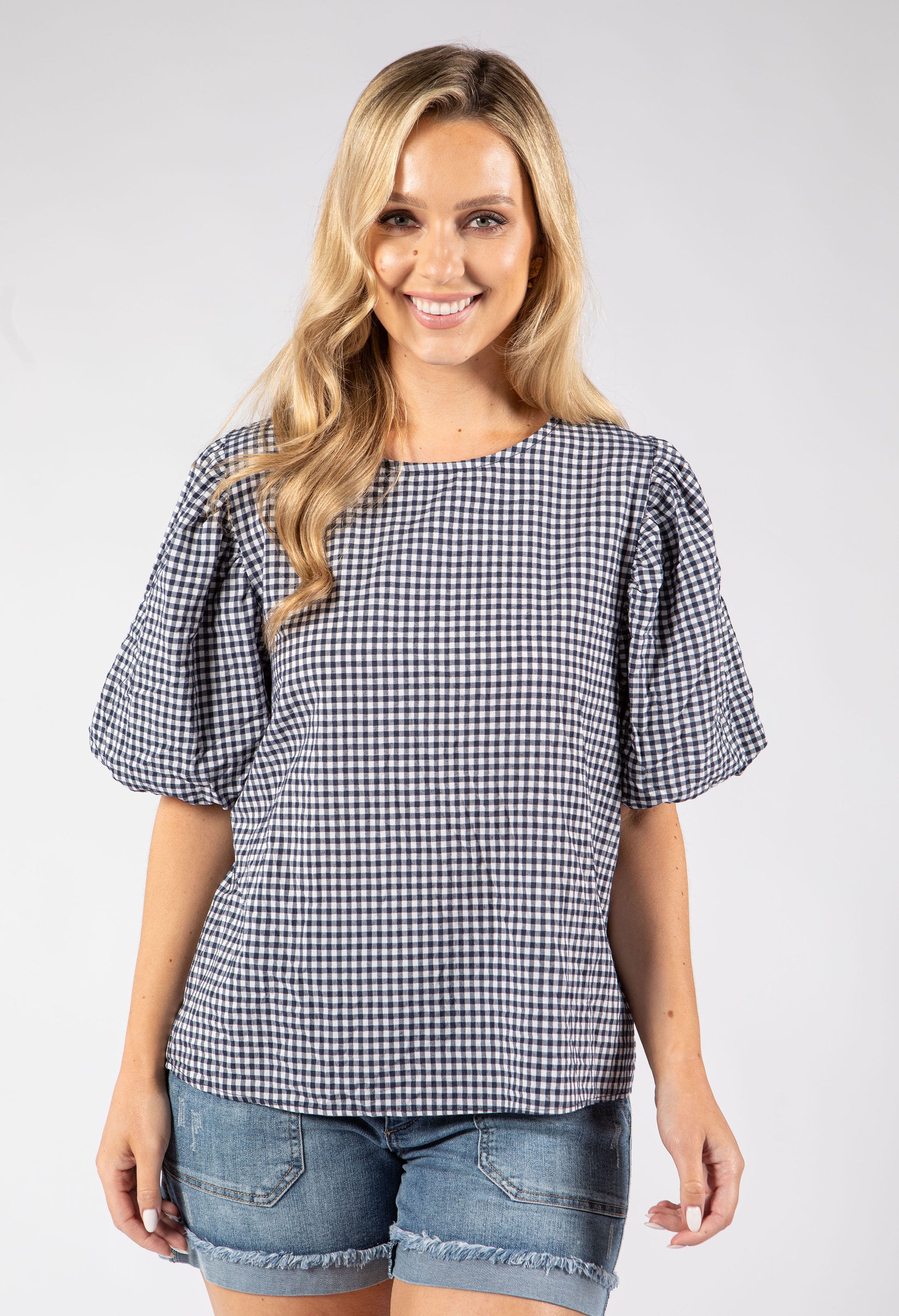 Woman wearing a checkered blouse and denim shorts on a white background