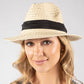 Woman wearing a straw hat with a black band on a gray background