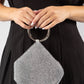Silver beaded handbag held by a person wearing a black dress.