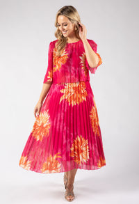 Woman wearing a pink dress with orange floral patterns on a white background
