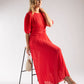 Woman in a red dress sitting on a chair against a white background