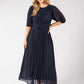 Woman wearing a navy blue dress with puff sleeves on a white background