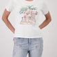 Woman wearing a white t-shirt with a graphic design and light blue jeans on a white background