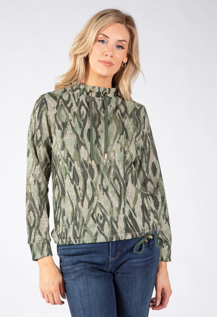 A woman modeling a green and beige abstract patterned hoodie with drawstrings waist.