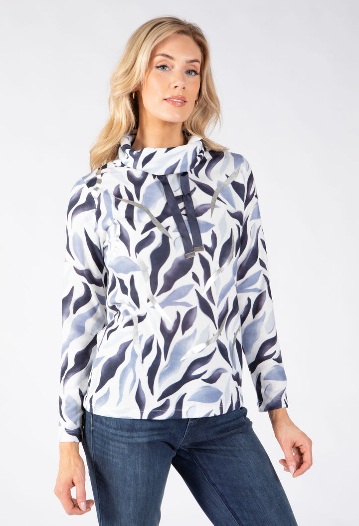 A woman modeling a long-sleeve high-neck blouse with a blue and gray abstract leaf pattern on a white background.