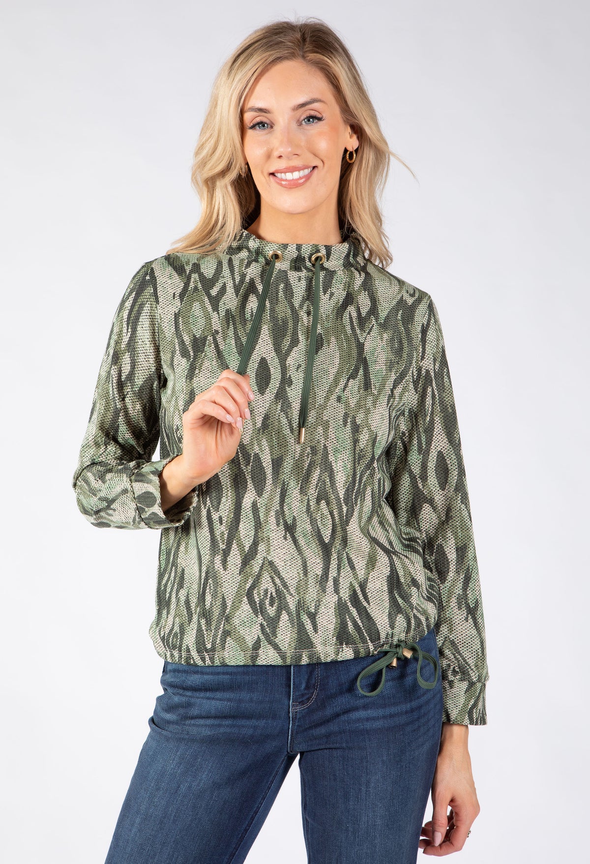A woman modeling a sage green and olive green abstract patterned long-sleeve top with a drawstring waistband.