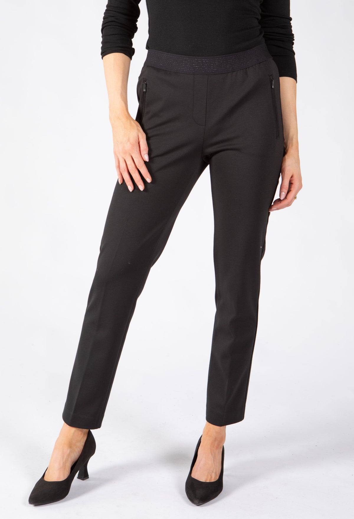 A model wearing slim-fit black trousers with a textured waistband. Features side zip pockets. 