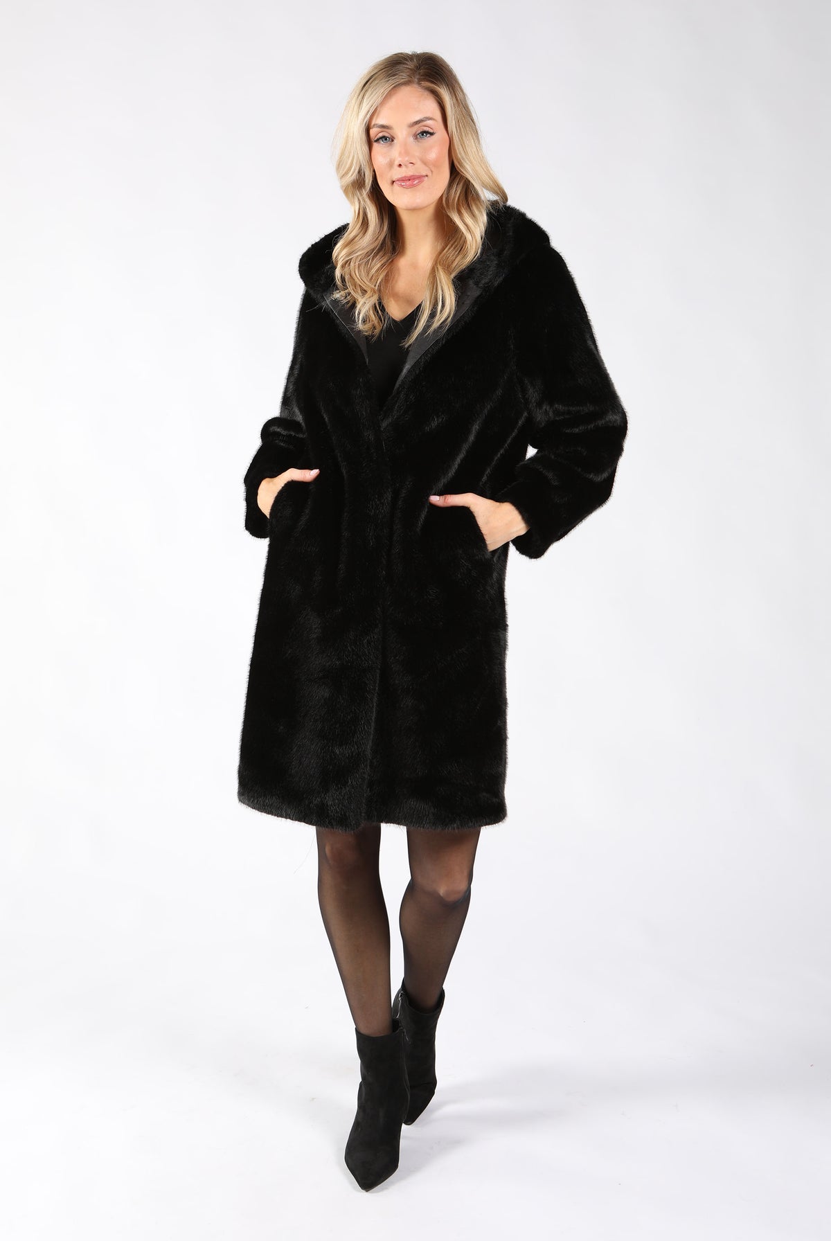 A woman modeling a black faux fur coat with a shawl collar and front pockets.