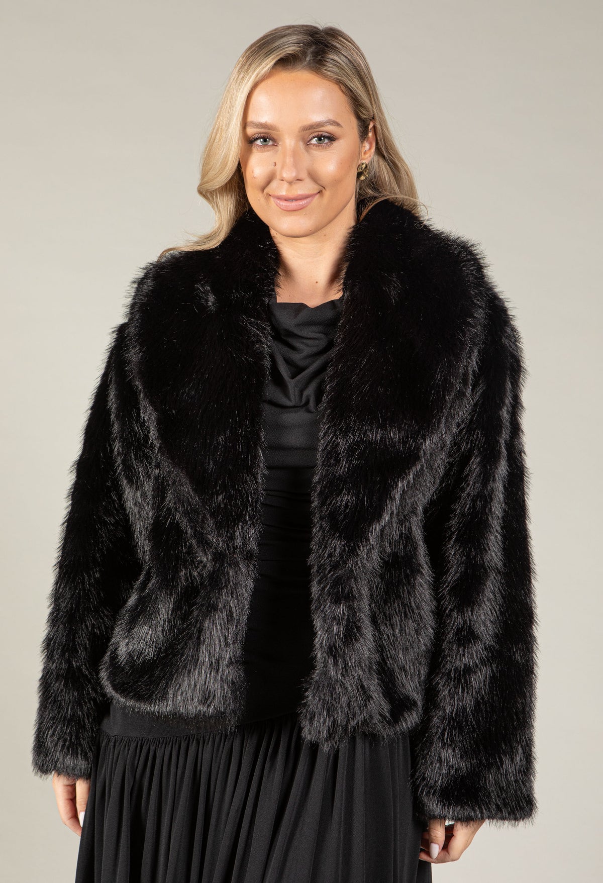A woman modeling a black faux fur jacket with a wide collar.