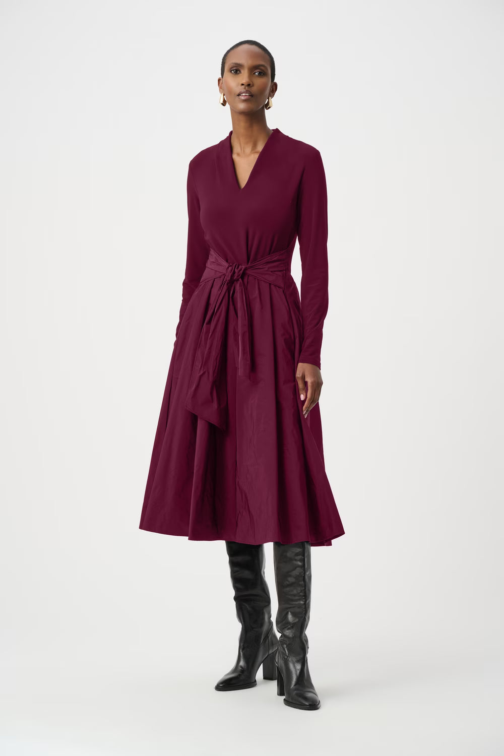A model wearing a plum long-sleeve wrap-style midi dress with a tied waist and a flared skirt.