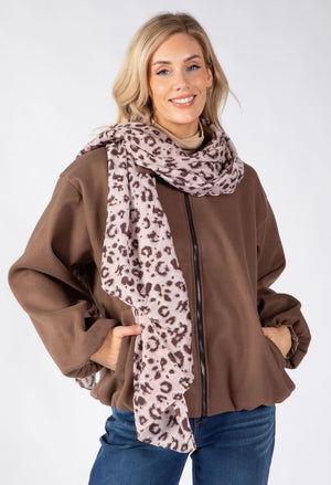 A woman modeling a brown zip-up jacket and a leopard-print scarf in front of a light gray studio background.