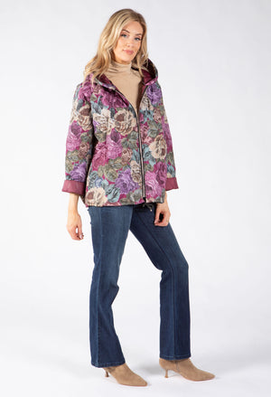 A woman modeling a floral patterned hooded jacket with purple, pink, and green tones.